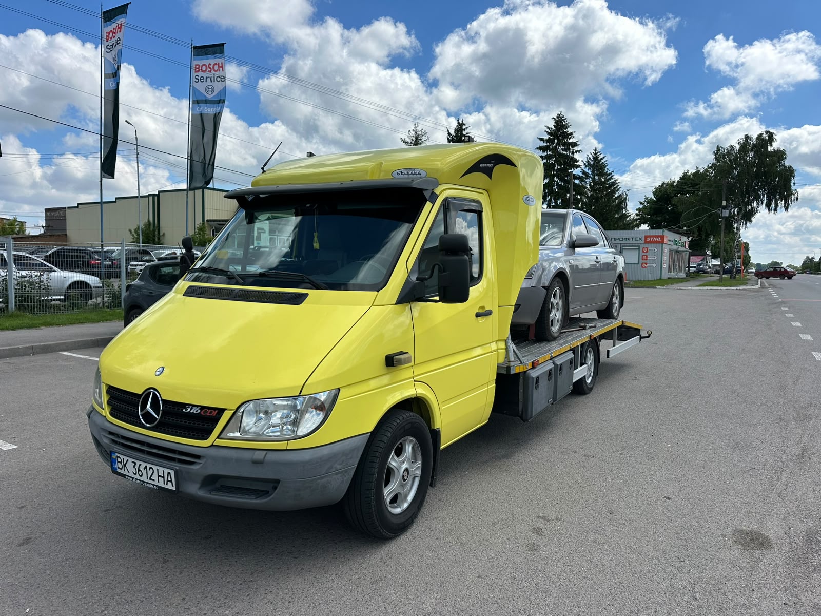 Жовтий евакуатор перевозить автомобіль дорогою